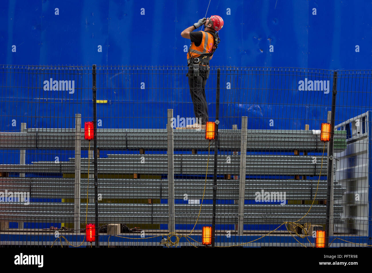 Ein Bauarbeiter überwacht das Anheben mit Hilfe eines Krans Fußboden neu in die oberen Stockwerken an der neuen Entwicklung hohe Bebauung bei 22 Bishopsgate in London City - der Capital District, am 21. August 2018 in London, England. 22 Bishopsgate ist ein kommerzielles Wolkenkratzer im Bau in London, Vereinigtes Königreich. Es wird ein prominenter Ort auf Bishopsgate besetzen, in der City von London Financial District, und ist 278 m hoch mit 62 Geschichten zu stehen. Das Projekt ersetzt eine frühere Plan für einen 288 m hohen Turm mit dem Namen Pinnacle, auf dem Bau im Jahr 2008 begonnen wurde, aber sus Stockfoto