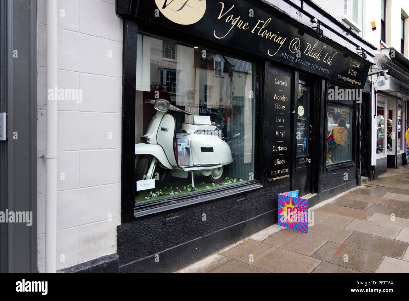 Vogue Bodenbeläge und Vorhänge mit einem lambretta Scooter Fenster anzuzeigen. Die Broad Street, Wells, Somerset, Großbritannien Stockfoto