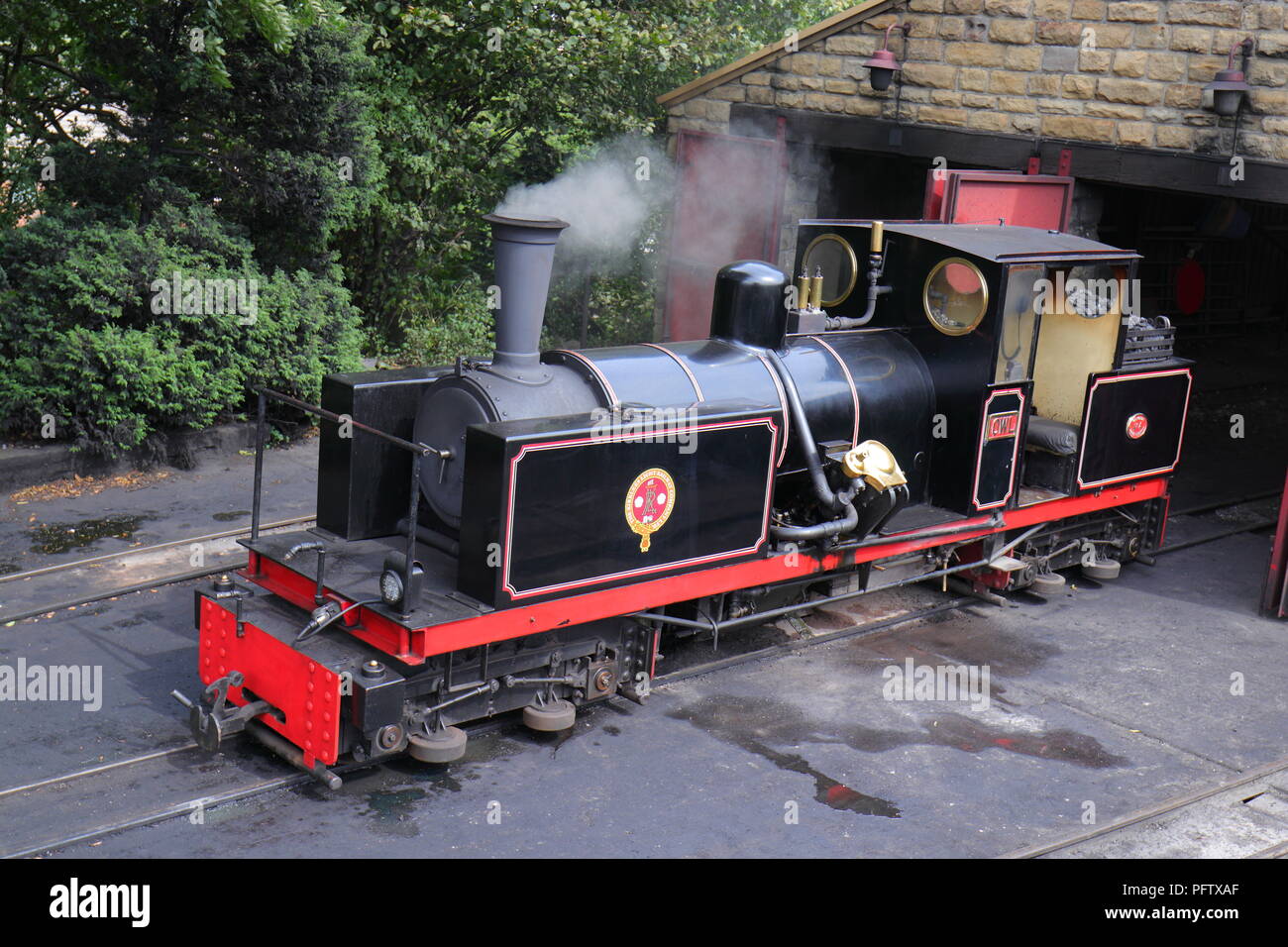 Eine schmalspurige Dampfeisenbahn sitzt im Leerlauf außerhalb eines Lokschuppen in Kirklees Light Railway in West Clayton, West Yorkshire Stockfoto