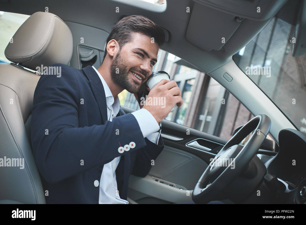 Junge attraktive Geschäftsmann im Auto trinken Kaffee und Gespräch über das Telefon Stockfoto