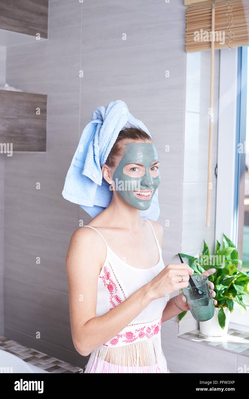 Frau Anwendung mask feuchtigkeitsspendende Creme im Gesicht in den Spiegel zu schauen. Mädchen kümmert um Ihrem Teint layering Feuchtigkeitscreme. Hautpflege spa Stockfoto