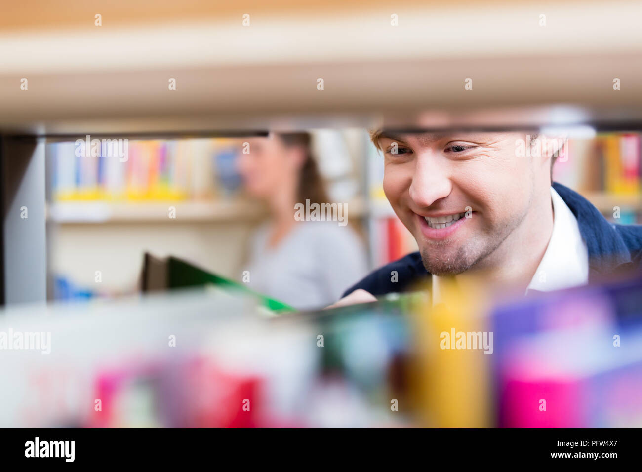 Der Mensch auf der Suche über Haltbarkeit von Büchern auswählen, um die Lautstärke zu lesen Stockfoto