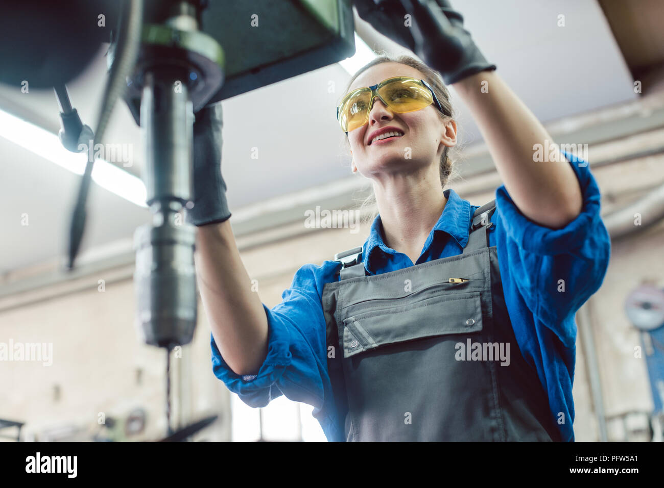 Frau Arbeiter in der Metallwerkstatt mit Sockel bohren Stockfoto
