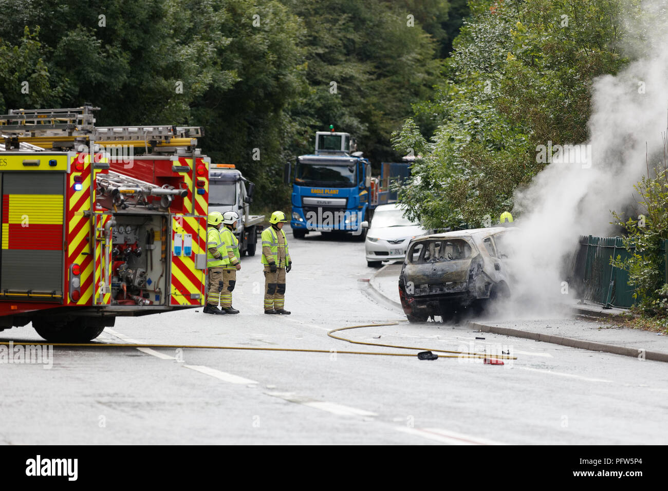 Die Feuerwehrleute sorgen sich ein Brand von einem roten Renault Auto in Crumlin, South Wales, Großbritannien Stockfoto