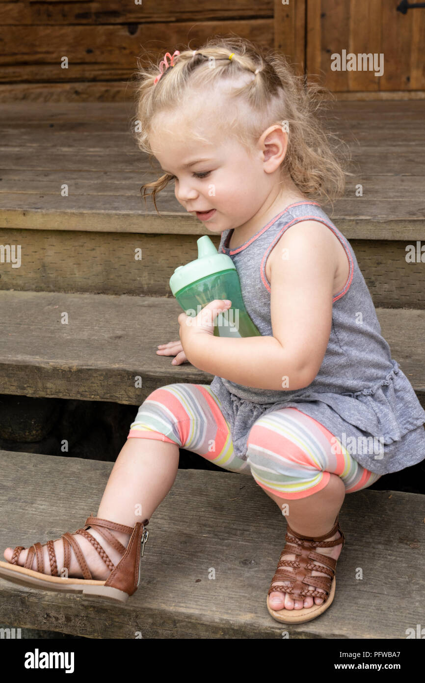 20 Monate alten Tochter scooting unten einige Schritte, während Ihr sippy cup Holding Stockfoto