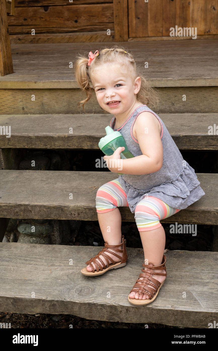 20 Monate alten Tochter scooting unten einige Schritte, während Ihr sippy cup Holding Stockfoto