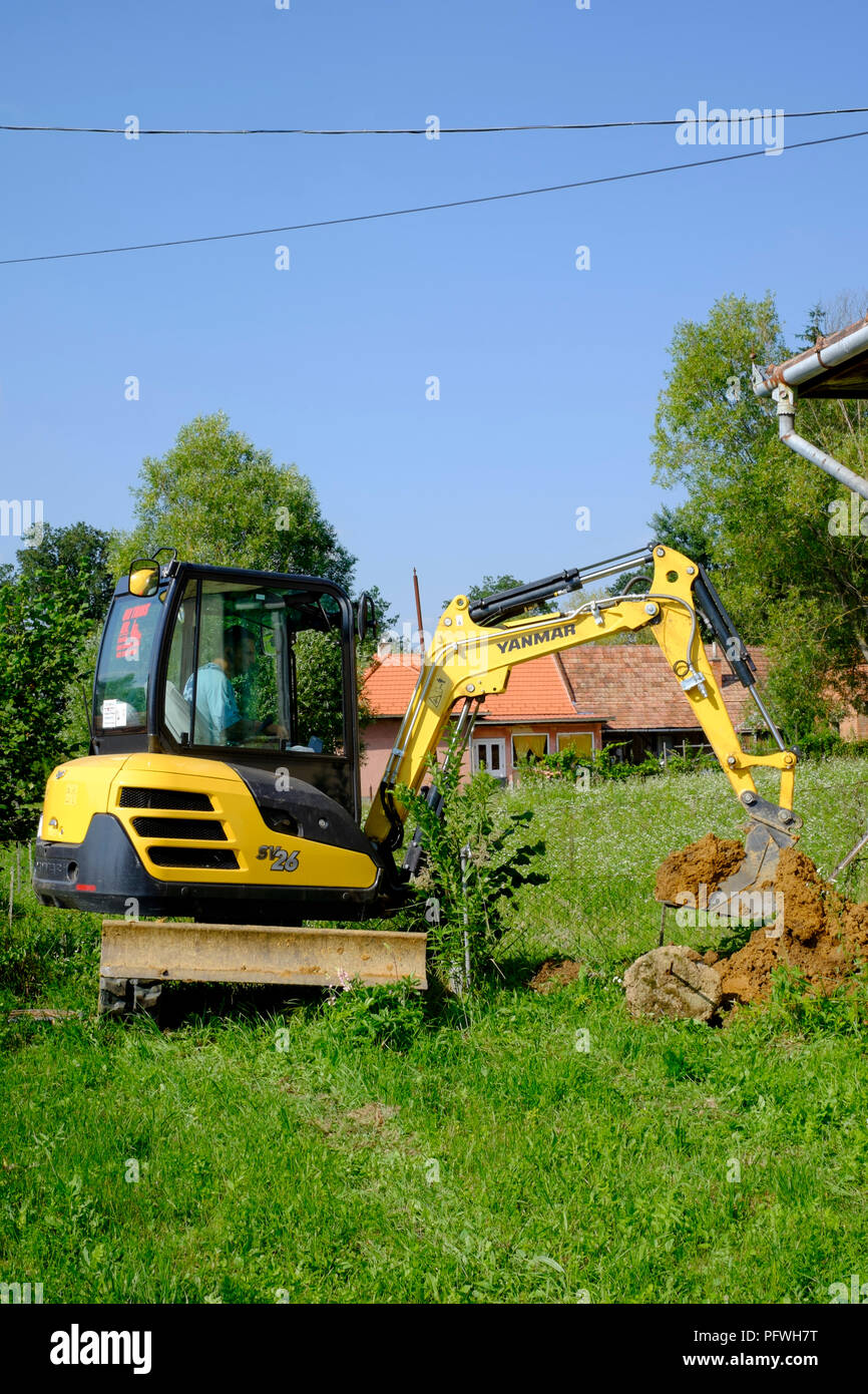 Mann mit einem mechanischen Digger in einem Garten ein Graben, Zala Ungarn dig Stockfoto