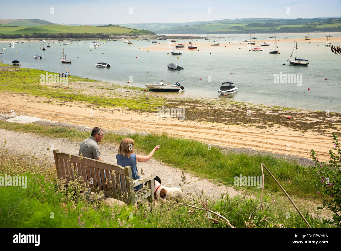 England, Cornwall, Rock, Paar saß auf waterfront Bank am Ufer des Flusses Camel Stockfoto