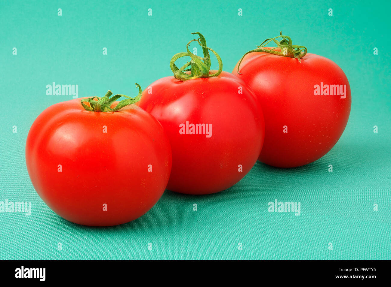 Drei rote Tomaten auf grünem Hintergrund Stockfoto
