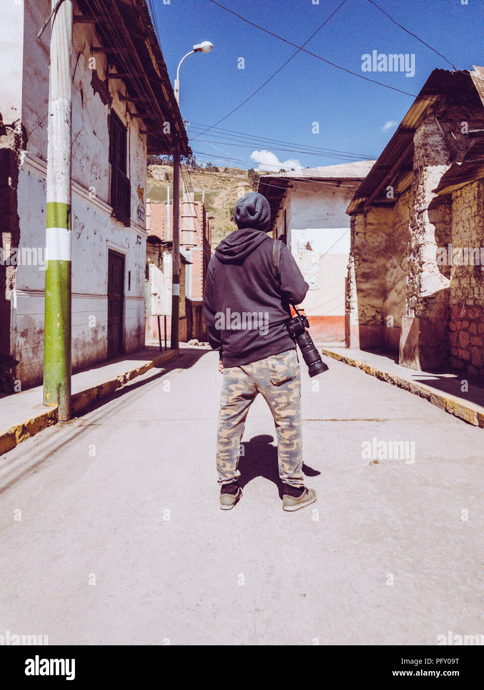 Wanderer Fotograf mit der Kamera auf der Schulter in das Dorf um ihn herum auf der Suche Stockfoto