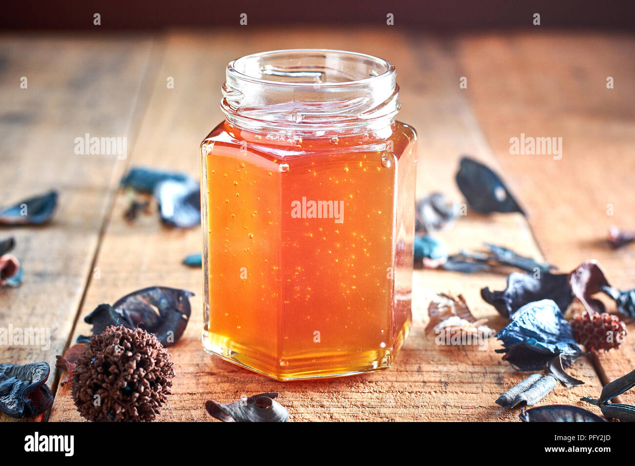 Glas Glas voll mit Honig auf Holztisch. Hoher Kontrast Stockfoto