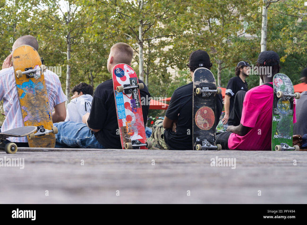 Skater ruhen - Vier Skater von hinten sitzen und lehnte sich auf ihren Skateboards gesehen. Stockfoto