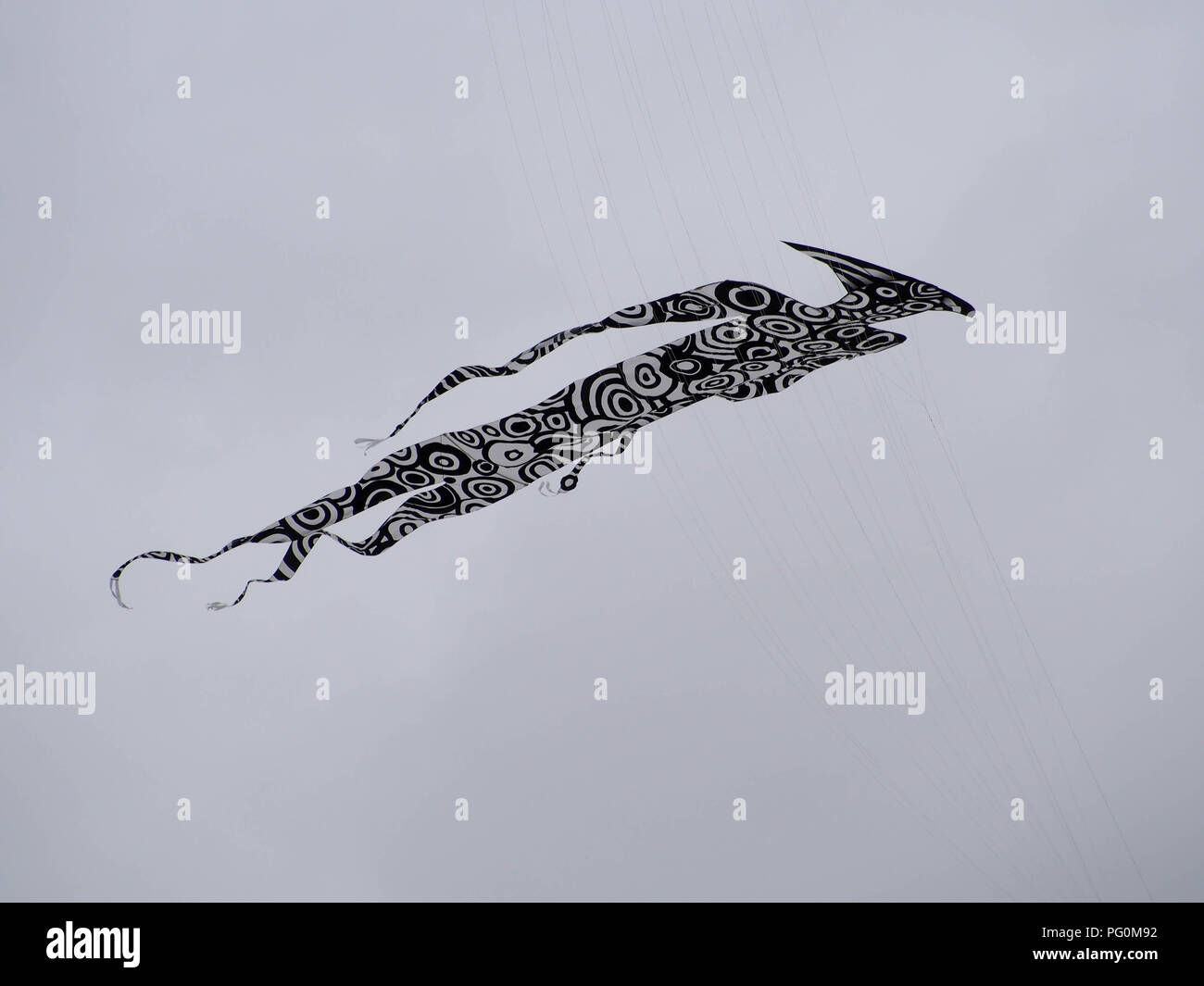 Einen Drachen in der Form eines menschlichen Fliegen gegen einen bewölkten grauen Himmel Stockfoto