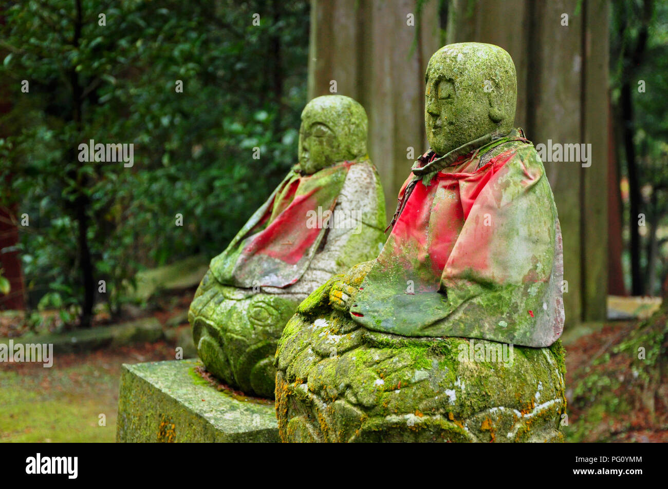 Alte bemoosten grünen Jizo (Bodhisattva) Statuen mit roten Mantel in der Nähe von kleinen Tempel auf dem Berg Shosha, Himeji, Japan Stockfoto