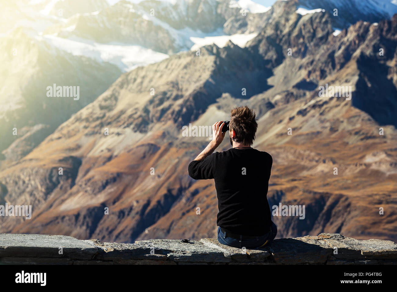 Mode touristische Mann aussehen Natur Blick auf Schnee und trockenen  Schicht von Berg durch ein Fernglas auf Sicht auf die Berge in der Schweiz  Stockfotografie - Alamy