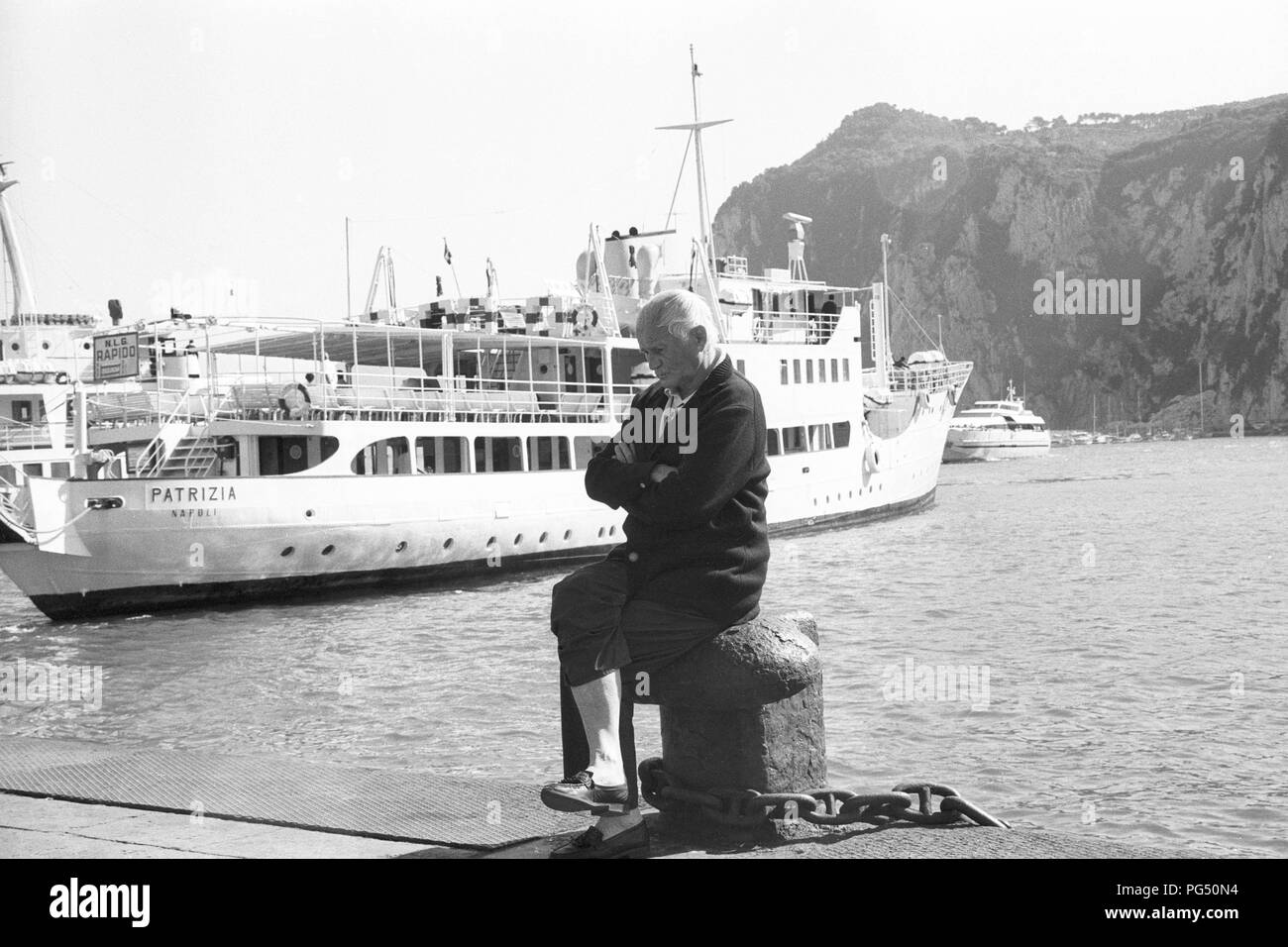 Der tschechische Schriftsteller Bohumil Hrabal sitzt auf einem Poller im Hafen von der italienischen Insel Capri. Stockfoto Der tschechische Schriftsteller Bohumil Hrabal sitzt auf einem Poller im Hafen von der italienischen Insel Capri. Stockfoto