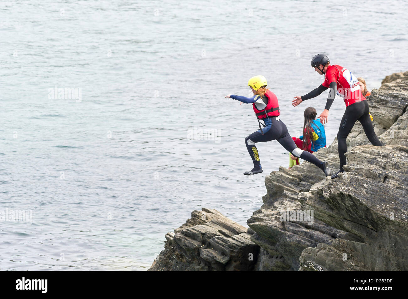 Urlauber coasteering auf der Landspitze in Newquay, Cornwall. Stockfoto