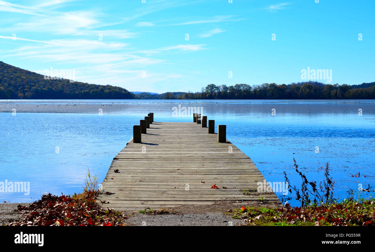 Holz dock Verlängerung über den See Wasser. Wunderschöne, ruhige und gelassene Bilder Bild von hölzernen Pier mit blauem Wasser und blauem Himmel, die fernen Hügel im Hintergrund. Stockfoto