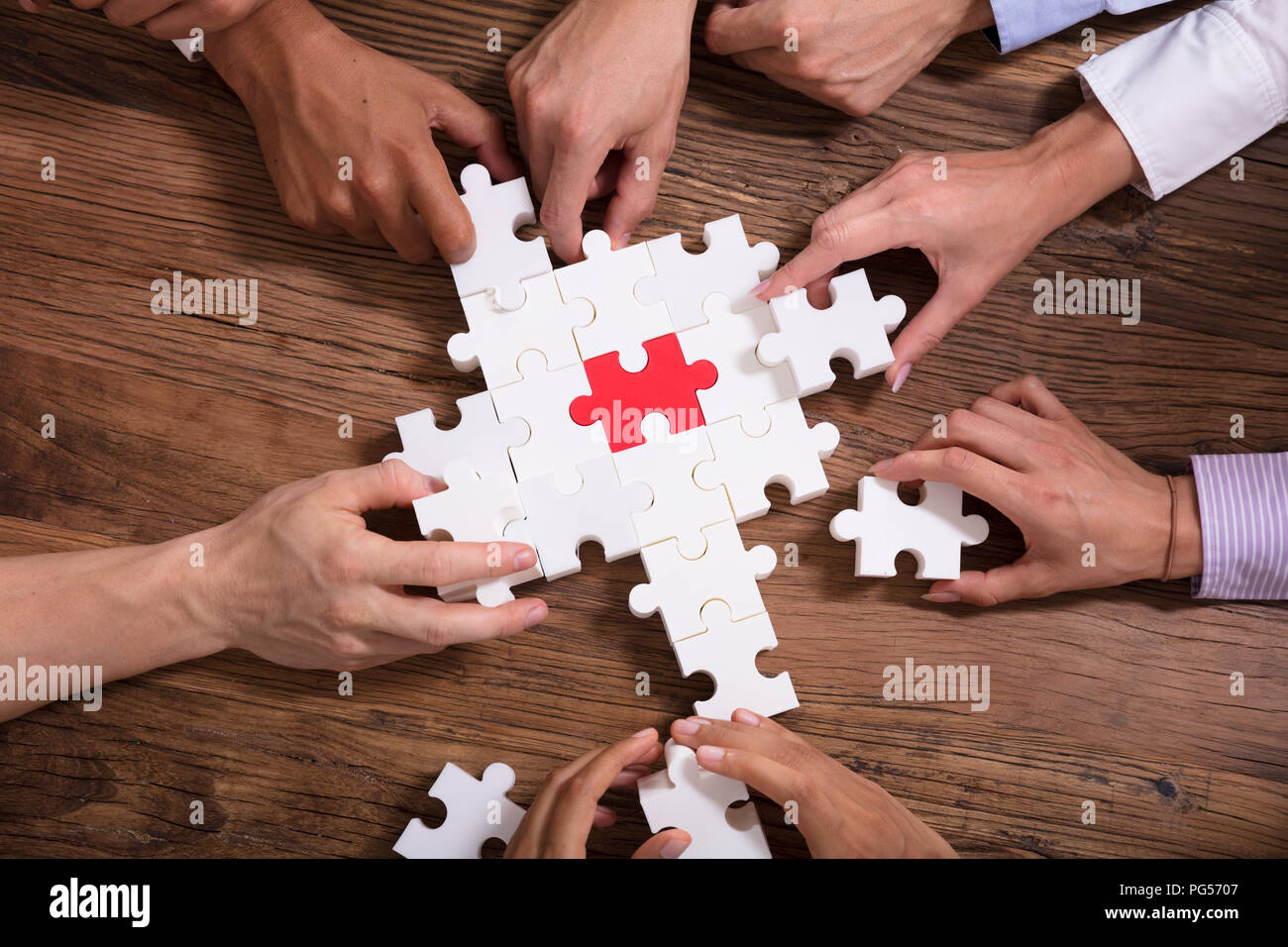 Erhöhten Blick auf Geschäftsleute Lösung Puzzle über Holz- Hintergrund Stockfoto