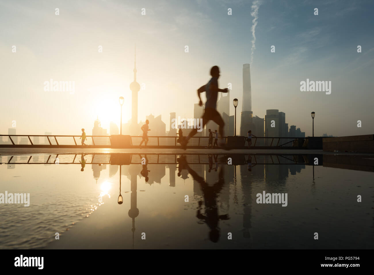 Menschen, die morgens am Huangpu-Fluss am Flussufer mit Shanghai downtown im Hintergrund laufen, in Shanghai, China. Stockfoto