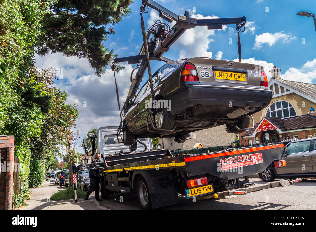 A 1992 Nissan Primera 2.0 LSI Automatik Limousine Auto auf einem Mercedes Atego recovery Lkw für Recycling, South Woodford, London, England angehoben Stockfoto