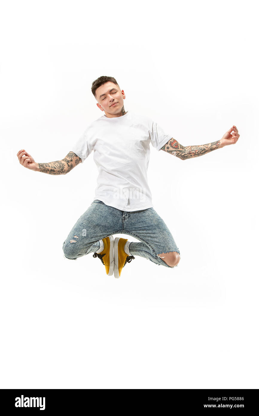 Yoga in Bewegung. Mid-Air Shot von Stattlichen glückliche junge Mann springen und in der Asana gegen Weiße studio Hintergrund posiert. Runnin Kerl in Bewegung oder Bewegung. Menschliche Gefühle und Mimik Konzept Stockfoto