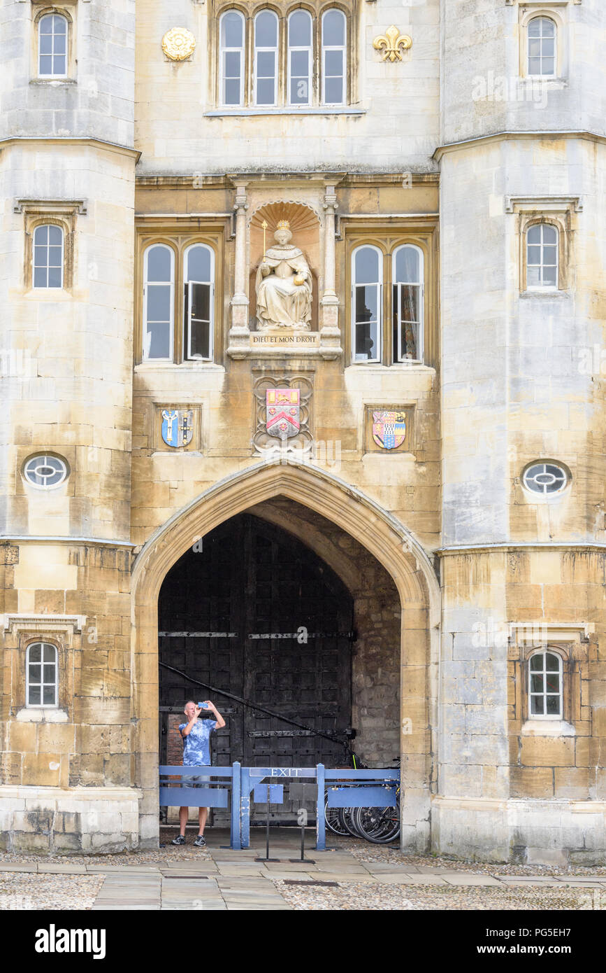 Ein männlicher Besucher macht ein Foto von der große Hof von der Veranda unterhalb der Statue der Königin Elizabeth I an der Wand des Queen's Gate am Trinity College, C Stockfoto