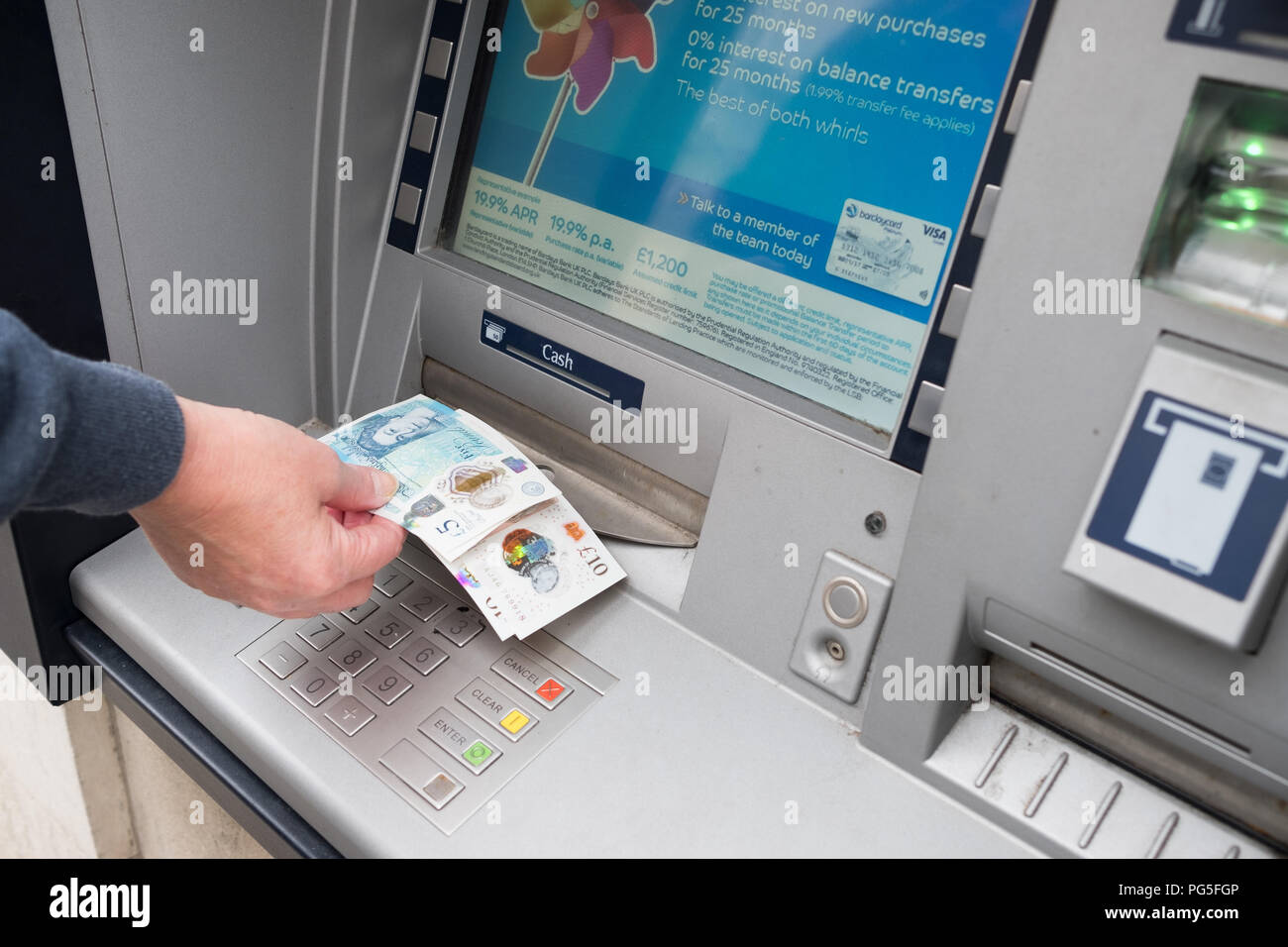 Eine Frau entfernt und 5 £ £ 10 Notizen von einem außerhalb der Barclays Bank, Loch in der Wand, Cash point maschine Stockfoto