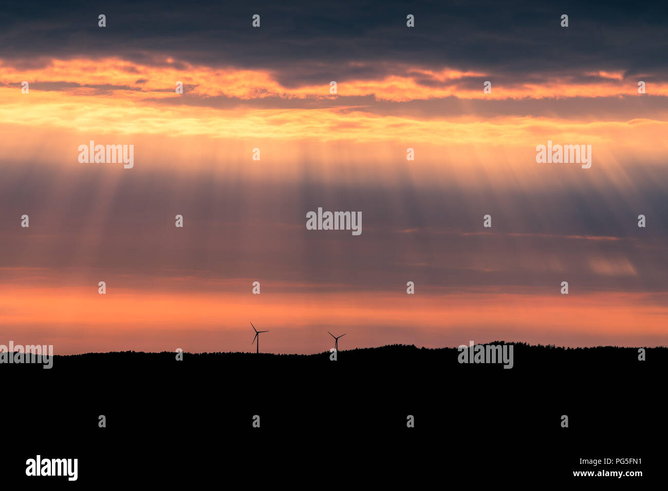 Zwei Windenergieanlagen auf einem Hügel bei Sonnenuntergang in der Nähe von Uddevalla, an der Westküste von Schweden. Sonnenstrahlen (besser bekannt als Sonnenstrahlen bekannt, Sonnenstrahlen. Stockfoto