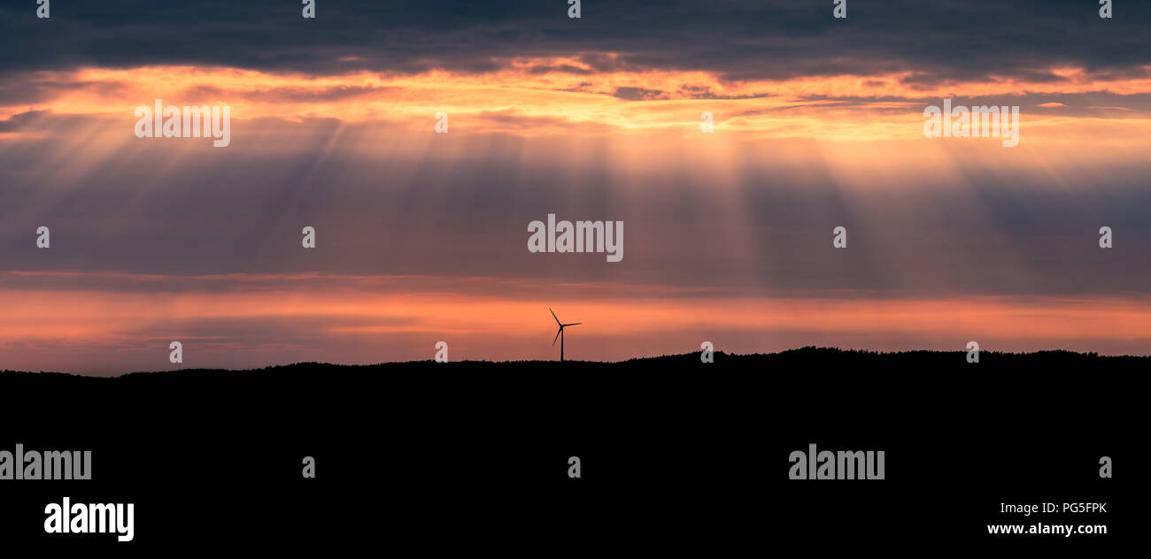 Eine einsame Windturbine auf einem Hügel bei Sonnenuntergang in der Nähe von Uddevalla, an der Westküste von Schweden. Sonnenstrahlen (besser bekannt als Sonnenstrahlen bekannt) Stockfoto