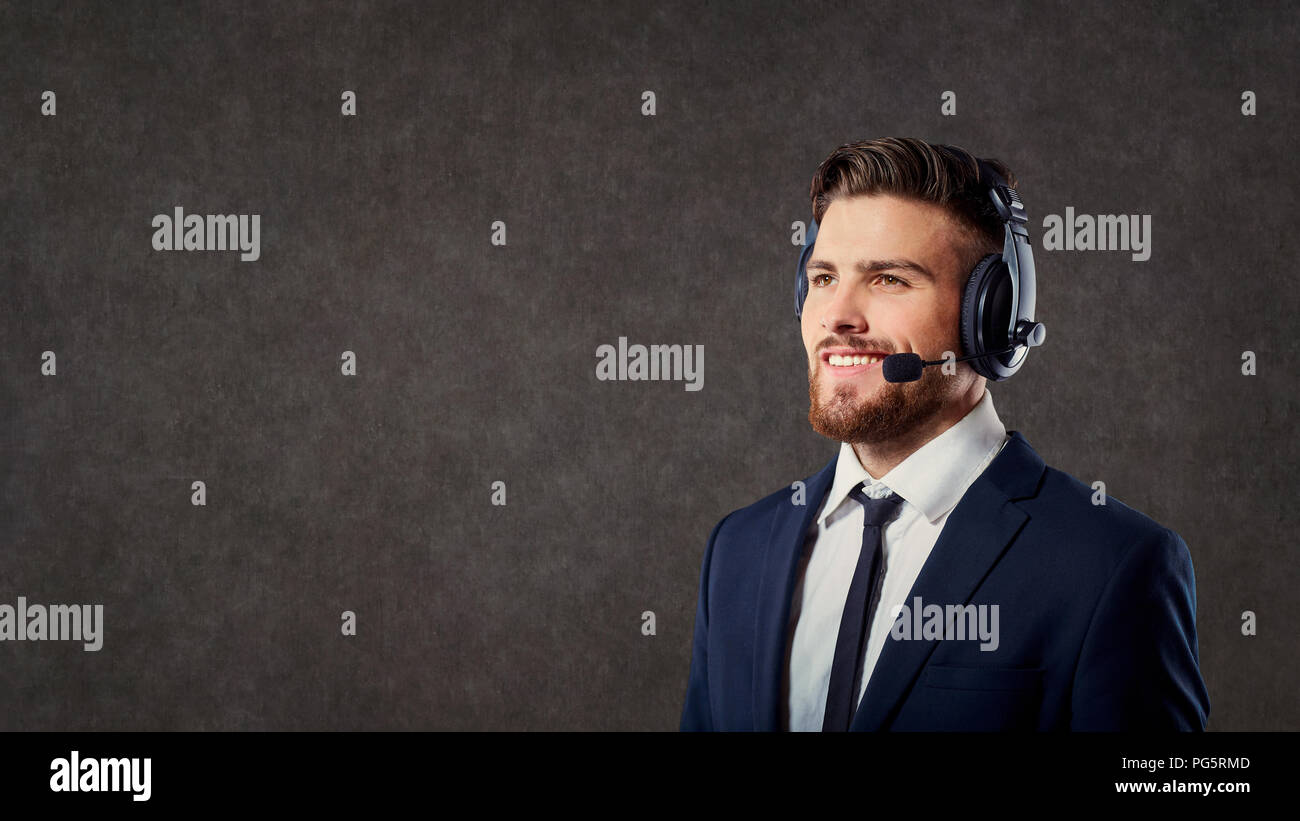 Ein männlicher Call Center Betreiber mit Headset auf grauem Hintergrund Stockfoto