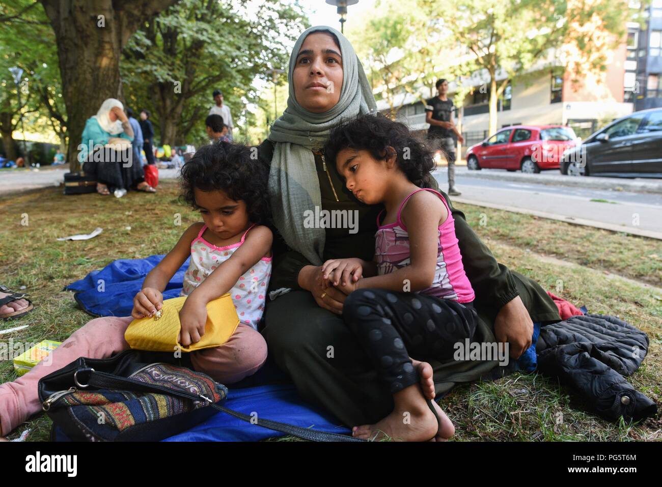 August 14, 2018 - Paris, Frankreich: Eine syrische Familie sitzen in einem öffentlichen Park in der Nähe von Porte d'Aubervilliers, wie sie für eine Wohltätigkeitsorganisation warten zu finden Not Unterschlupf für die Nacht. Die Familie der acht Mitglieder, zwei Eltern und sechs Kinder, kommen aus der Provinz Idlib und bemüht, Asyl in Frankreich für mehrere Monate im Kampf mit der Französischen Bürokratie regeln. Die 34-jährige Mutter, Kiraz Hamza, wird dargestellt mit ihren Zwillingstöchtern Fatima und Amna, im Alter von 3 und halb Jahre alt. Portrait dÕune Famille de Migranten Syriens ˆ la rue depuis Leur arrivee ein Paris, il y a Pres de huit Mois. Ils pas Stockfoto