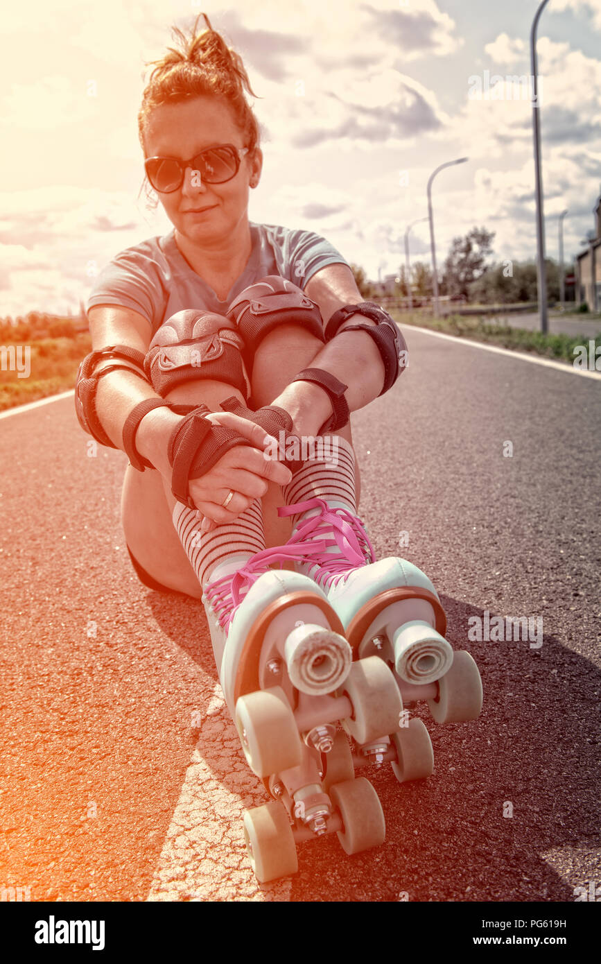 Frau, die in einem Jahrgang Rollschuhe, retro Quad skates Sitzen im Freien. Stockfoto