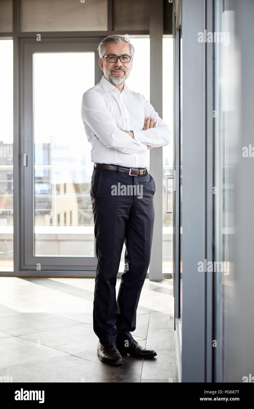 Portrait von lächelnden Geschäftsmann stand am Fenster Stockfoto