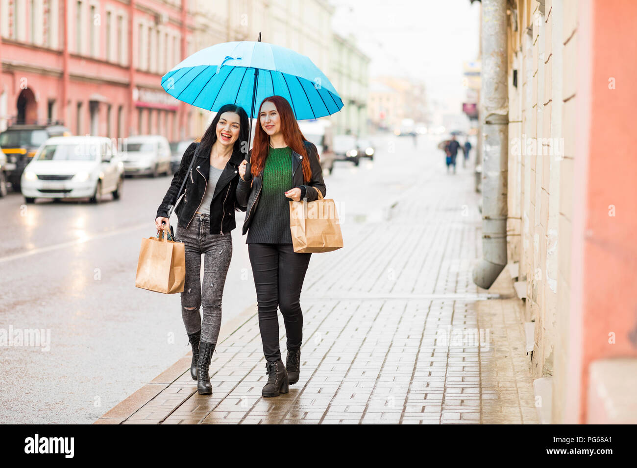 Zwei glückliche Frauen Shopping in der Stadt an einem regnerischen Tag Stockfoto