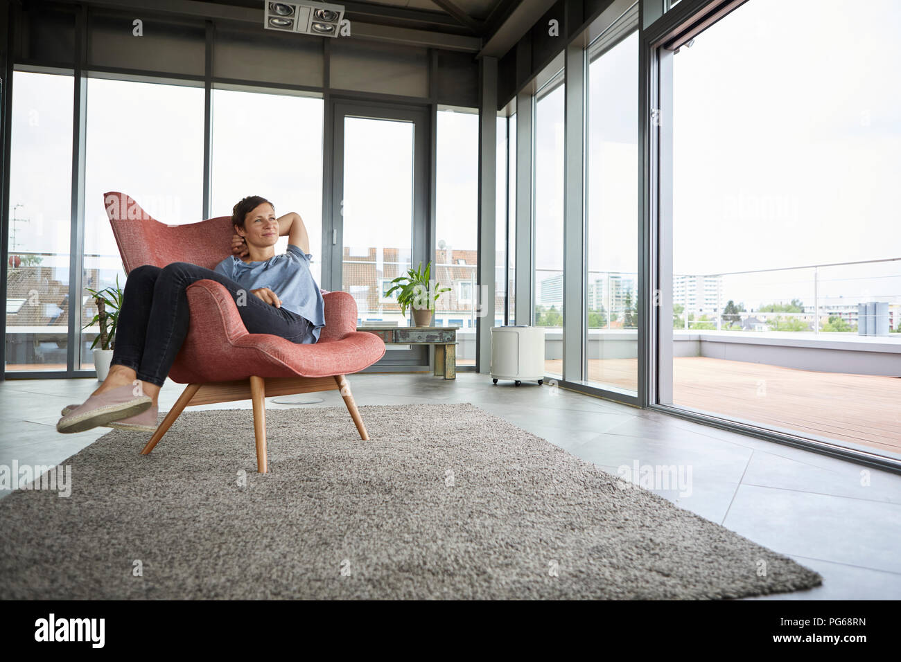 Frau sitzt im Sessel zu Hause entspannen Stockfoto