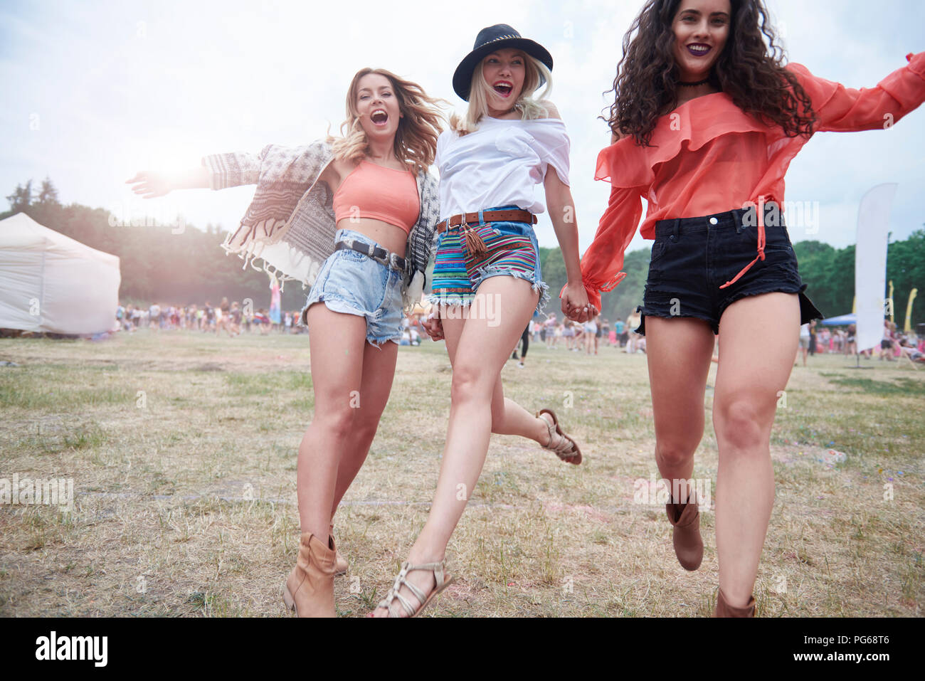 Fröhliche Freunde halten sich an den Händen und laufen auf ein Musik Festival Stockfoto