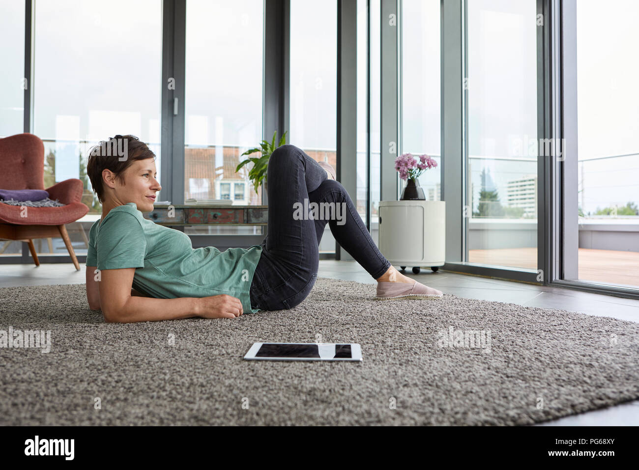 Frau auf dem Boden liegend zu Hause mit Tablet aus Balkon Tür Stockfoto