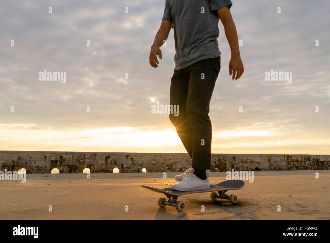 Junge Chinesen skateboarding an sunsrise nahe dem Strand Stockfoto