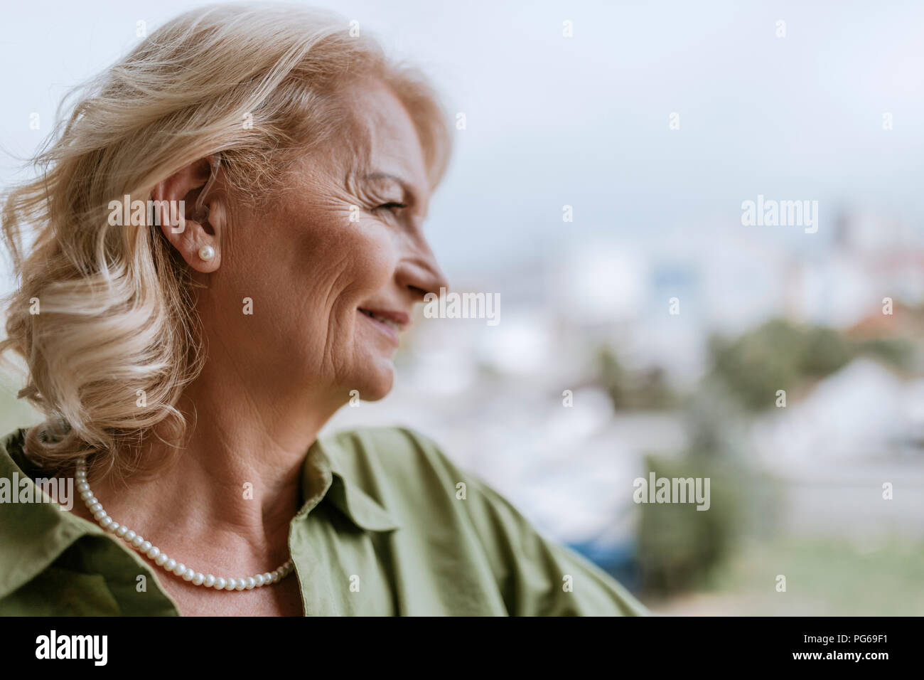 Lächelnde ältere Frau mit Hörgerät im Freien Stockfoto
