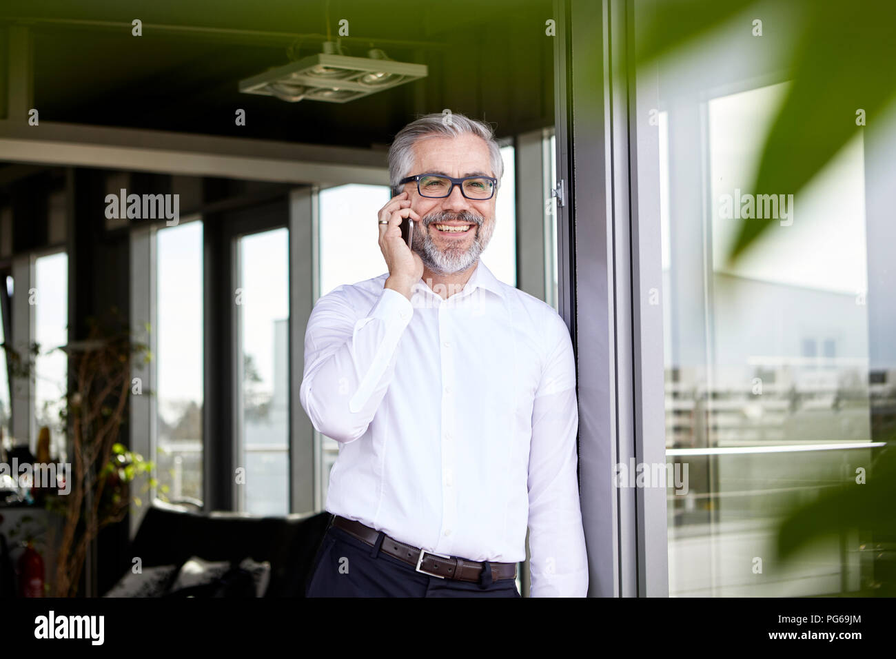 Lächelnd Geschäftsmann an französische Tür Gespräch am Handy Stockfoto