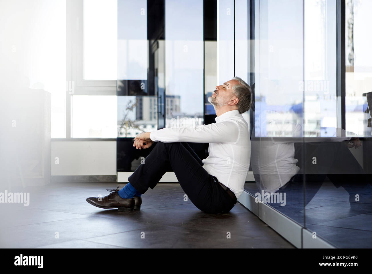 Geschäftsmann auf dem Fußboden sitzen im Büro mit geschlossenen Augen Stockfoto