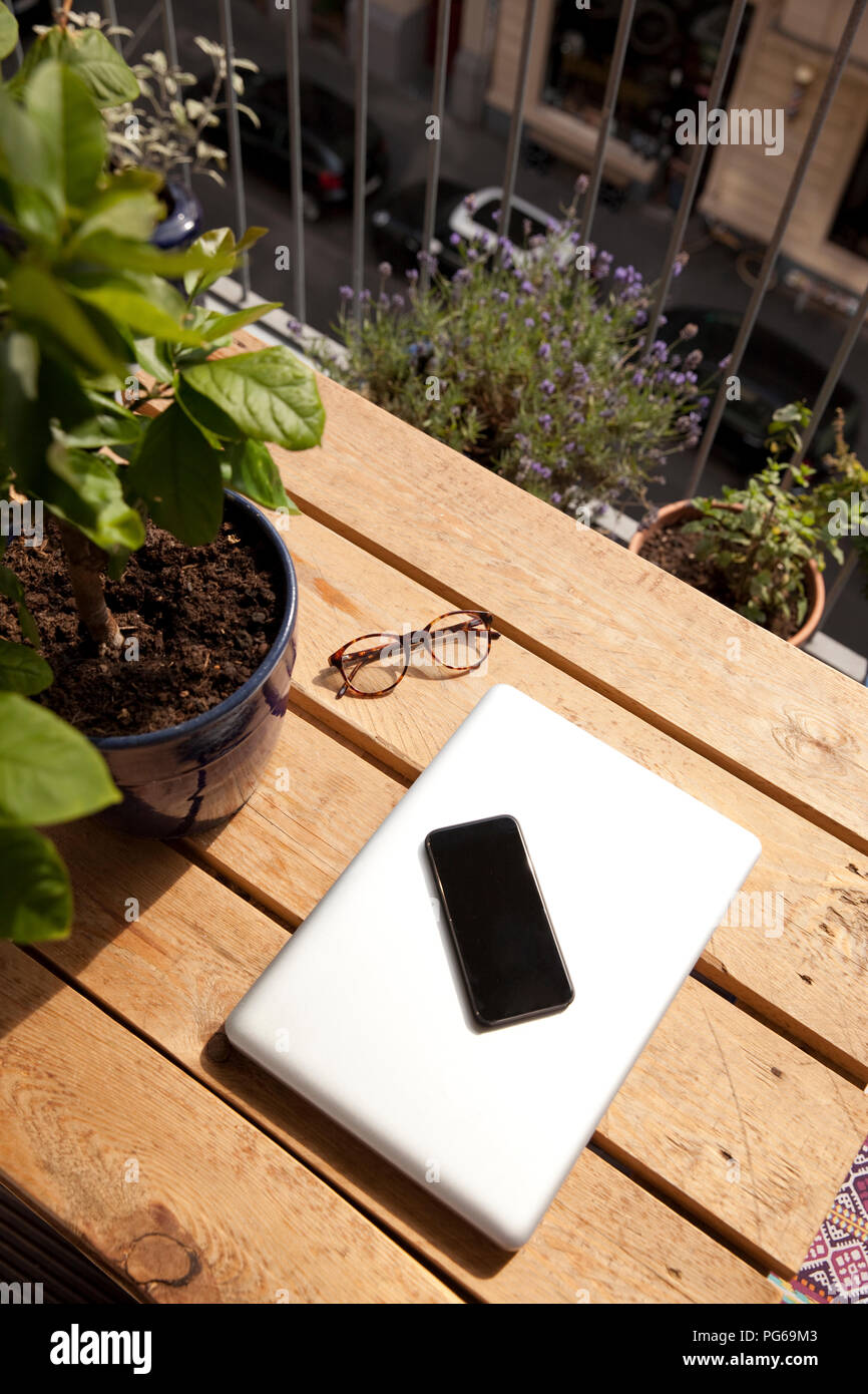 Smartphone, Laptop und Brillen auf Palette auf dem Balkon Stockfoto