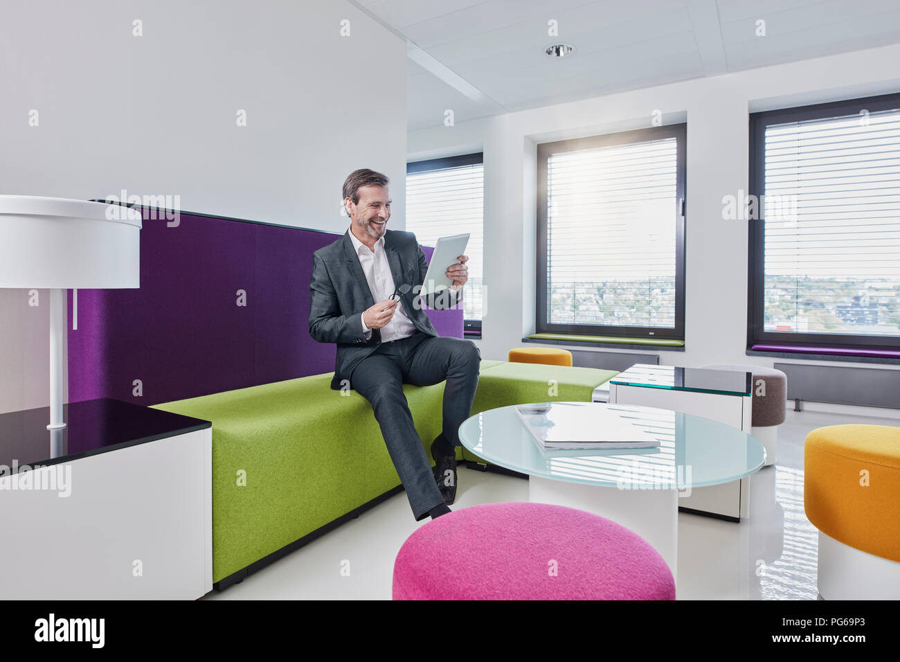 Happy Geschäftsmann mit Tablet-PC im Büro lounge Stockfoto