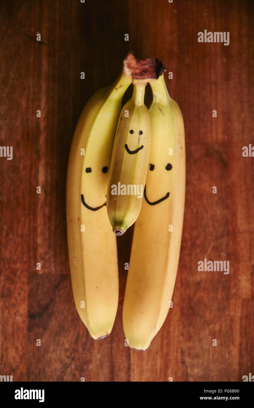 Haufen von zwei große und eine kleine Bananen mit smiley-Gesichter Stockfoto