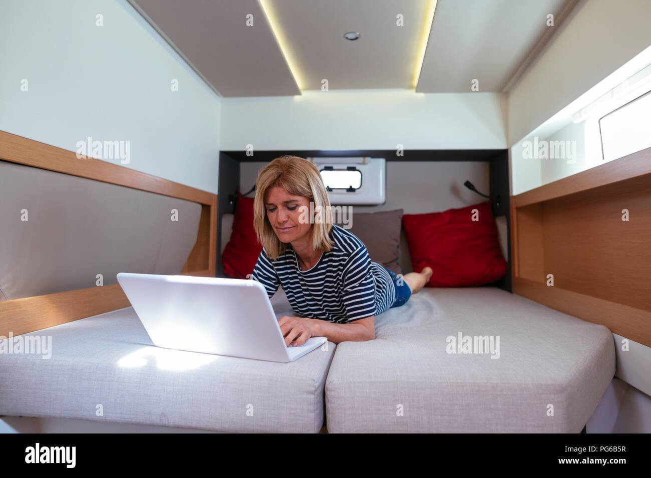 Reife Frau liegend auf Bett in einem Katamaran Kabine, mit Laptop  Stockfotografie - Alamy