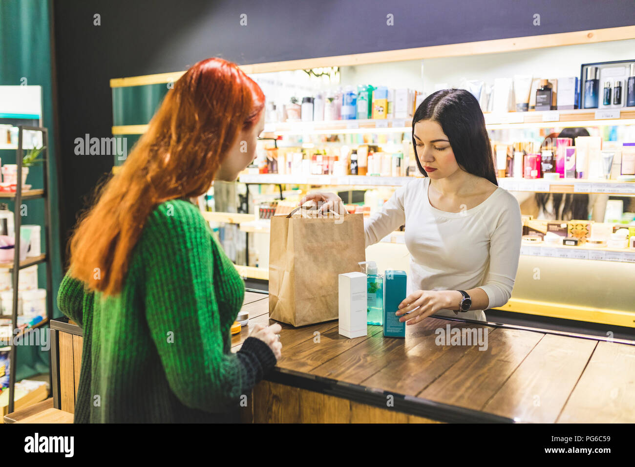 Verkäufer und Kunde Verpackung Produkte in Papier Beutel in einem kosmetik Shop Stockfoto