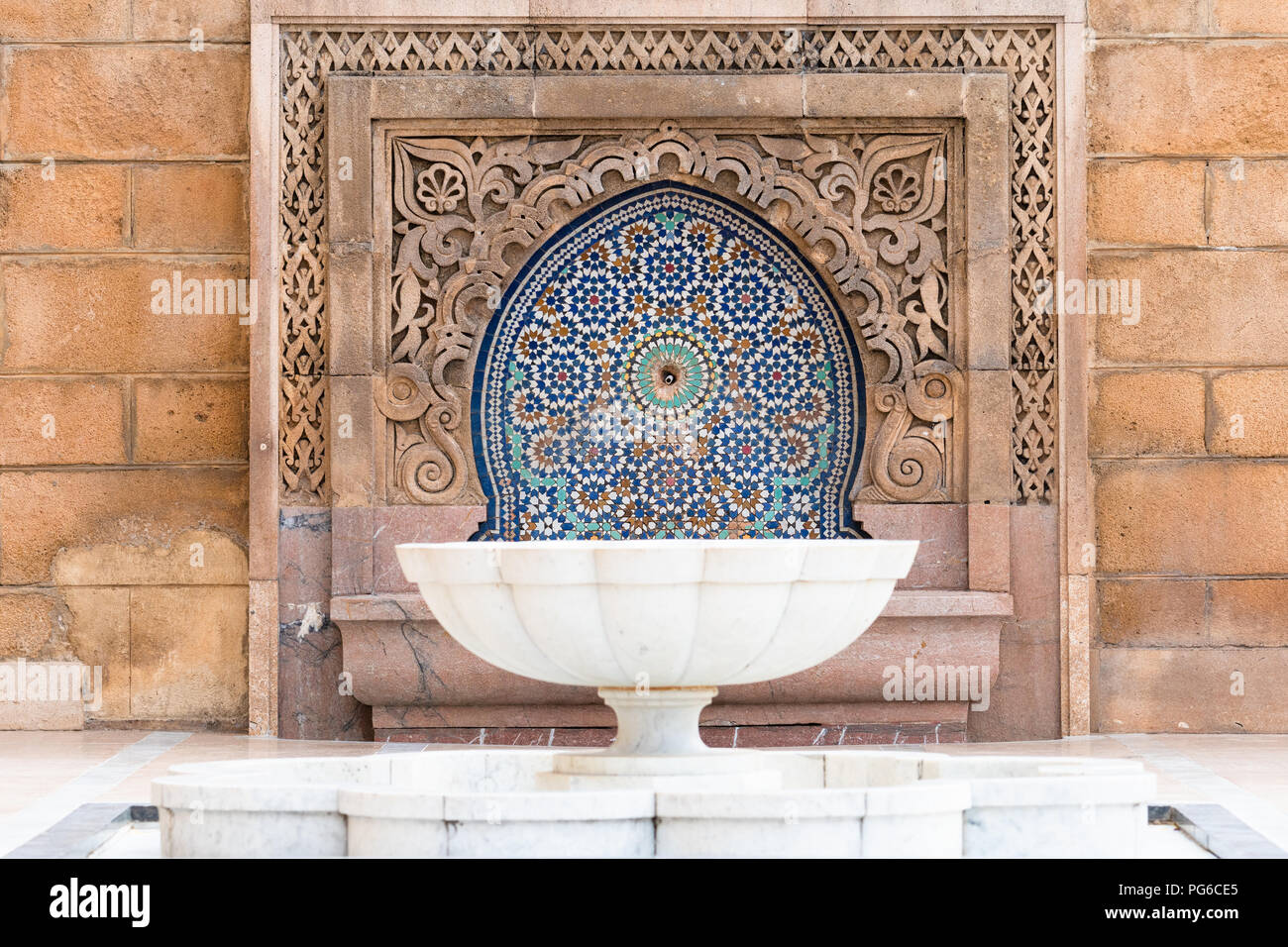 Weißer Marmor Brunnen und Fliesen- zellige mit geschnitzten Stein Surround am Moschee Hassan in Rabat, Marokko Stockfoto