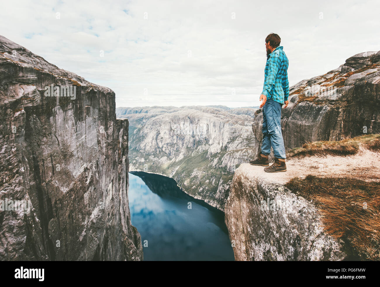 Explorer Mann stand auf einer Klippe über Fjord solo Reisen Wandern in Norwegen Abenteuer lifestyle Wochenende Reise Kjerag Rocky Mountains Stockfoto