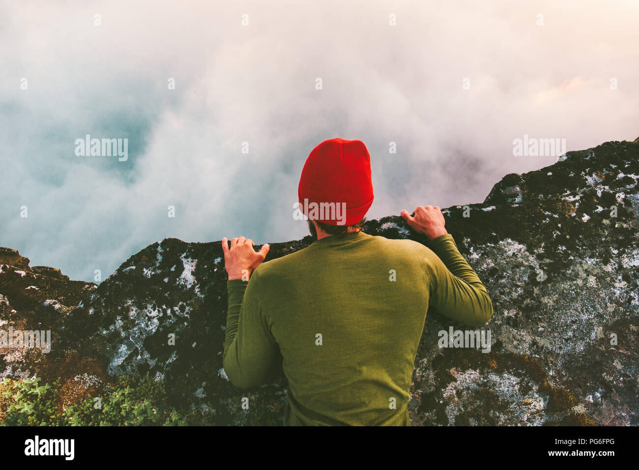 Mann, liegend am Rande Klippe über Wolken den Blick in den Abgrund Berge reisen Abenteuer lifestyle extreme Ferien Stockfoto